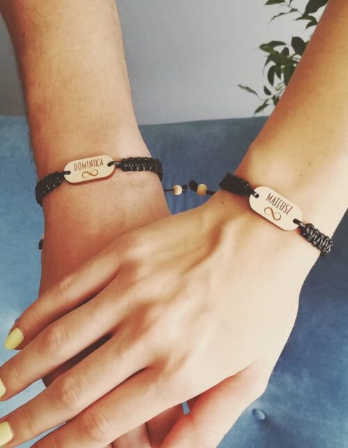 Dwie bransoletki dla par ze znakiem nieskończoności na drewnianych zawieszkach z personalizowanym grawerem, sznurki w różnych kolorach.