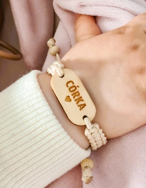 Bransoletka dla niemowlaka z naturalną, drewnianą zawieszką z grawerem imienia, na regulowanym, ręcznie plecionym sznurku.